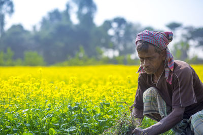 Rear view of person on field against yellow flowering plants