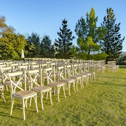 Empty chairs on field against clear sky