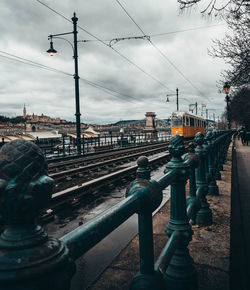 Bridge over railroad tracks in city against sky