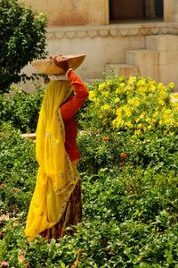 Side view of woman carrying container on head at park