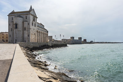 Buildings by sea against sky in city