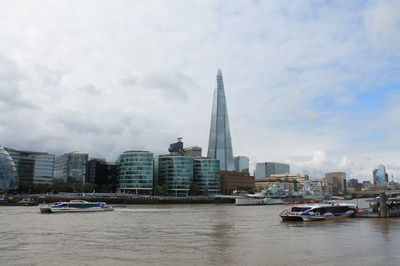 View of buildings at waterfront against cloudy sky