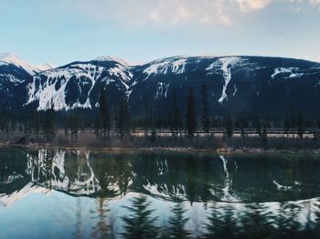 Scenic view of lake by snowcapped mountain against sky