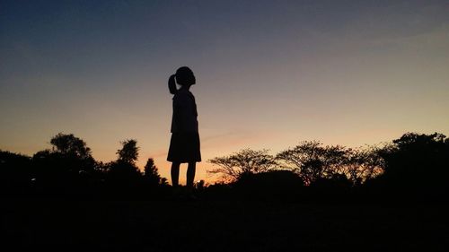 Silhouette of girl standing against sunset