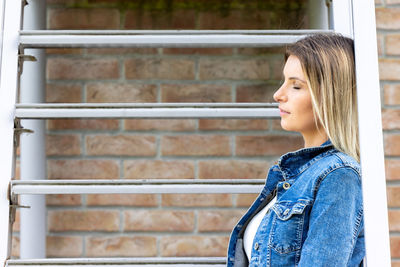 Young woman standing against wall