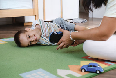 Kid with health problem playing toy cars with mother at home. child having cerebral palsy