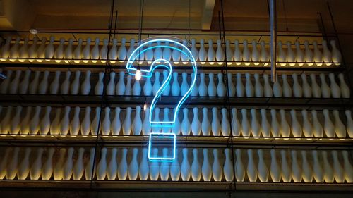 Low angle view of illuminated question mark symbol on bowling pins