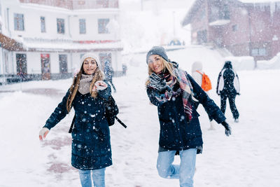 Beautiful young women throwing snowballs at the camera