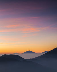 Scenic view of silhouette mountains against romantic sky at sunset