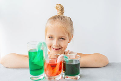 Portrait of boy playing with drinking glass against white background