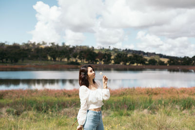 Full length of woman standing by lake against sky