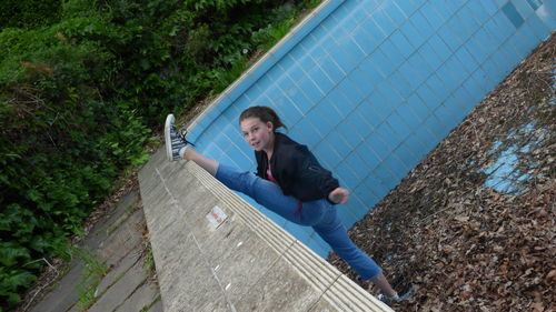 Portrait of girl stretching legs in abandoned swimming pool