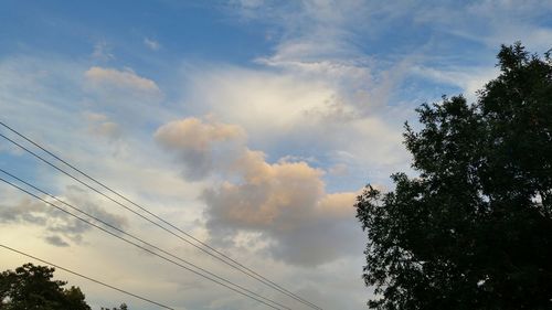 Low angle view of power lines against cloudy sky