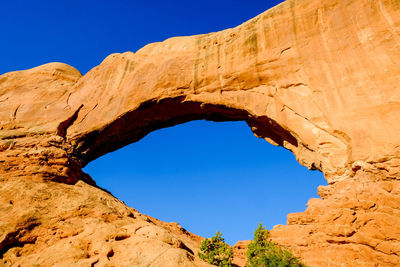 Low angle view of rock formation against clear blue sky