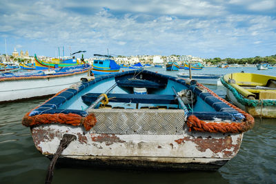 Fishing boats moored at harbor against sky