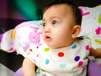 Portrait of cute baby girl on bed at home