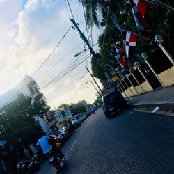 Cars on city street by buildings against sky