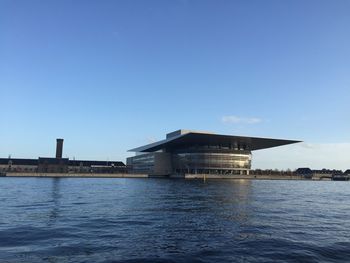 Building by sea against clear blue sky