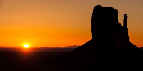 Silhouette rock formation at monument valley against orange sky during sunset