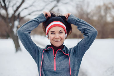 Portrait of smiling woman standing on road during winter