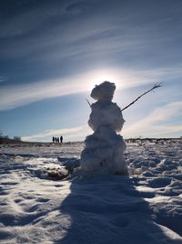 Snow covered land against sky during sunset