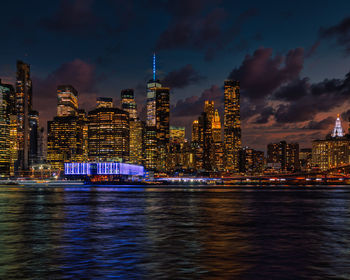 Illuminated modern buildings in city against sky at night