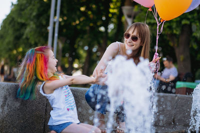 Woman holding balloons sitting with daughter