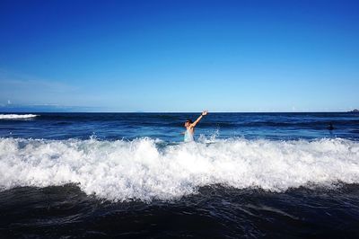 Man surfing on sea against clear blue sky