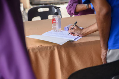 Midsection of man holding paper while sitting on table