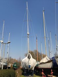 Sailboats moored in sea against clear blue sky