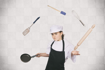 Portrait of girl wearing chef uniform juggling kitchen utensils