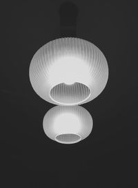 Low angle view of illuminated pendant light over black background