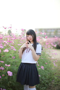 Portrait of woman by pink flowers standing on field