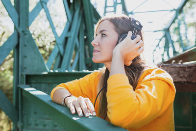 Woman listening to music with her old headphones on an abandoned iron bridge.