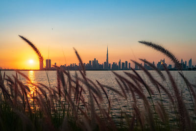 Silhouette city against sky during sunset