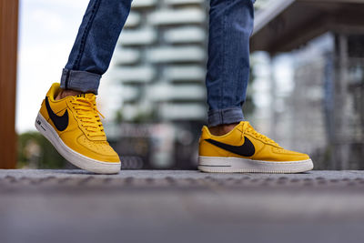 Low section of person standing on yellow shoes