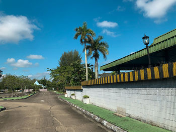Road by trees against blue sky
