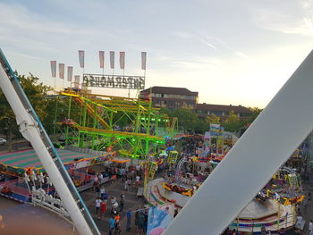 People at amusement park against sky in city
