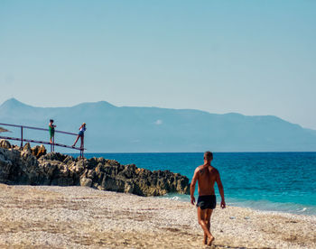 Man standing on beach against clear sky