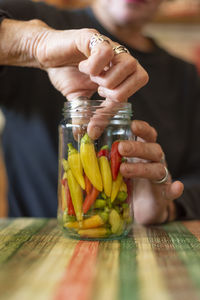 Hands of woman are putting hot peppers in jar and preparing it for winter.