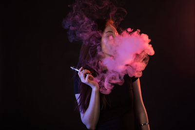 Midsection of woman holding flower against black background