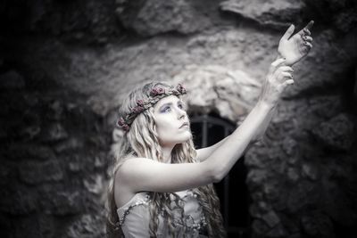 Woman with arms raised standing against wall