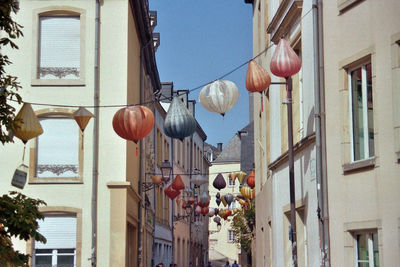 Low angle view of lanterns hanging on street amidst buildings