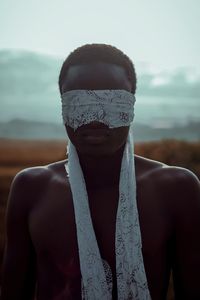 Portrait of shirtless man standing against sky