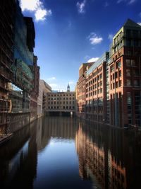 Canal amidst buildings in city against sky