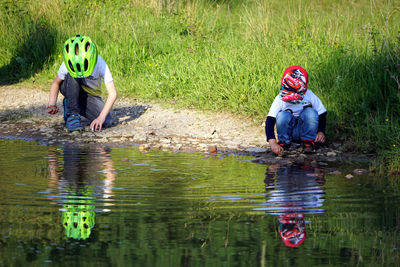 Full length of men sitting on lake