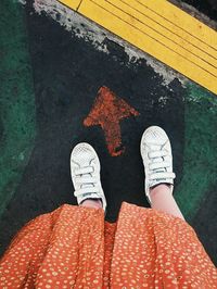 Low section of woman standing by arrow symbol on road