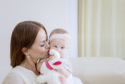 Woman kissing baby girl at home