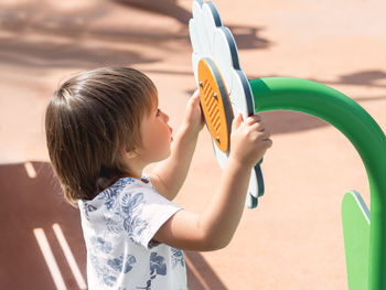 Little boy on children playground. toddler wants to be heard on other side of sound - conducting toy