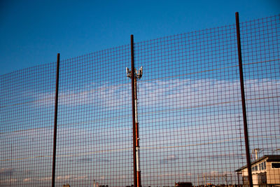 Low angle view of fence against blue sky